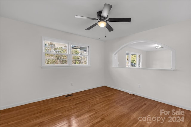 empty room with wood-type flooring and ceiling fan with notable chandelier