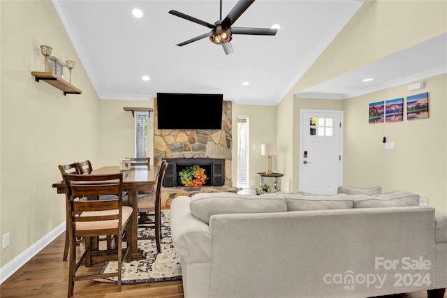 living room with ceiling fan, vaulted ceiling, hardwood / wood-style flooring, a fireplace, and ornamental molding