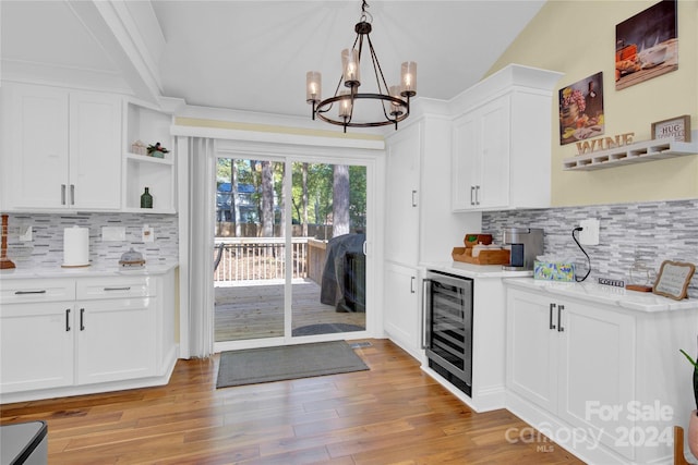 kitchen with decorative backsplash, light hardwood / wood-style flooring, white cabinetry, and beverage cooler