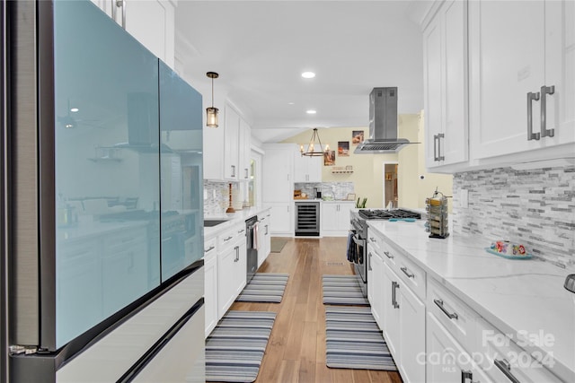 kitchen featuring wine cooler, range hood, appliances with stainless steel finishes, white cabinets, and light wood-type flooring