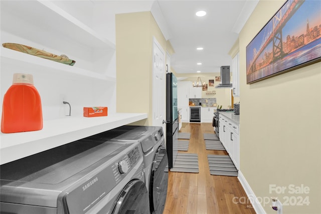 laundry area featuring wine cooler, light hardwood / wood-style flooring, and independent washer and dryer