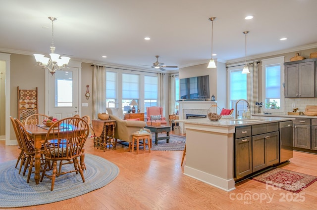 kitchen with decorative backsplash, a healthy amount of sunlight, a center island with sink, and decorative light fixtures