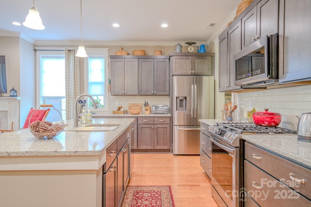 kitchen with decorative light fixtures, light stone countertops, appliances with stainless steel finishes, and sink