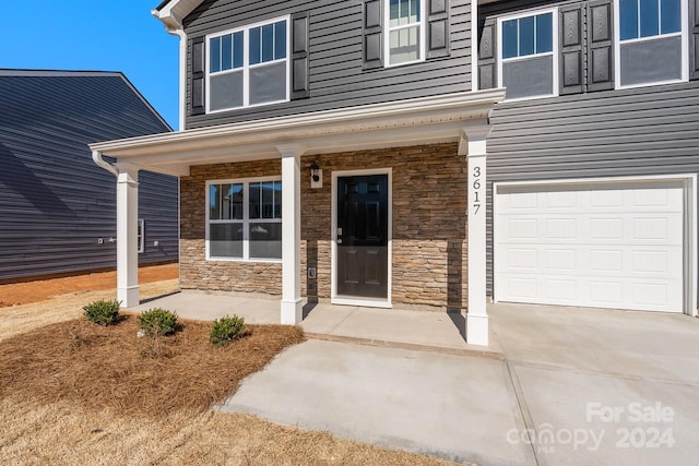 view of exterior entry with covered porch and a garage