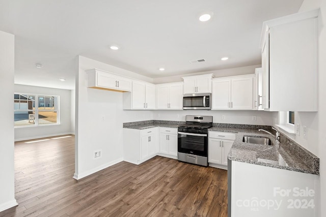 kitchen featuring white cabinetry, sink, dark hardwood / wood-style floors, dark stone countertops, and appliances with stainless steel finishes