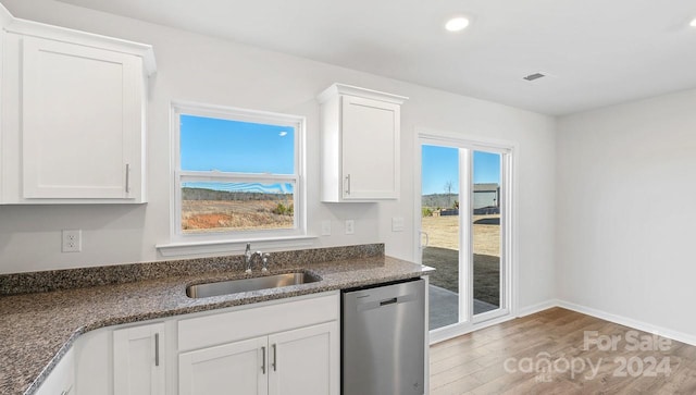 kitchen with white cabinetry, sink, stainless steel dishwasher, and hardwood / wood-style flooring