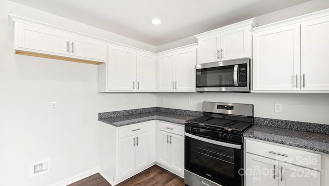 kitchen featuring white cabinets, dark hardwood / wood-style flooring, stainless steel appliances, and dark stone counters