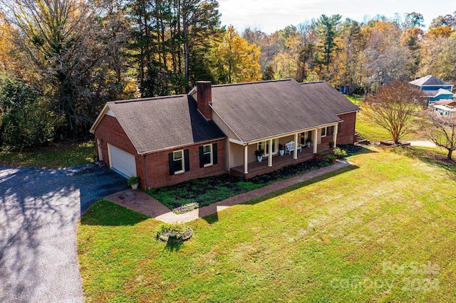 view of front facade with covered porch, a garage, and a front lawn