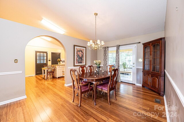 dining room featuring a notable chandelier, wood-type flooring, and lofted ceiling