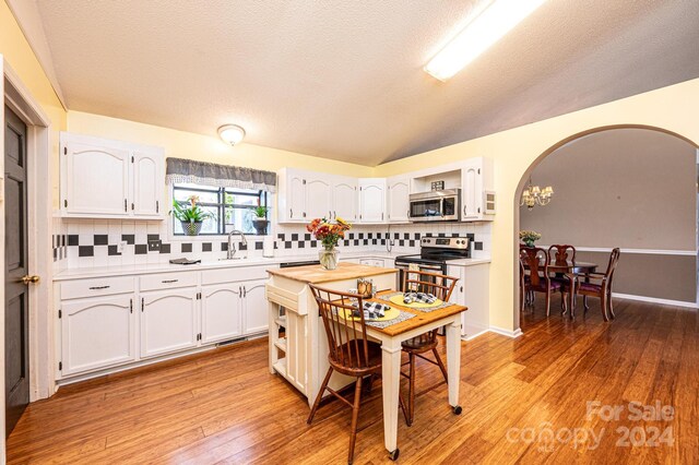 kitchen featuring white cabinets, stainless steel appliances, light hardwood / wood-style flooring, and tasteful backsplash