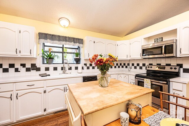 kitchen with appliances with stainless steel finishes, tasteful backsplash, sink, wood-type flooring, and white cabinets