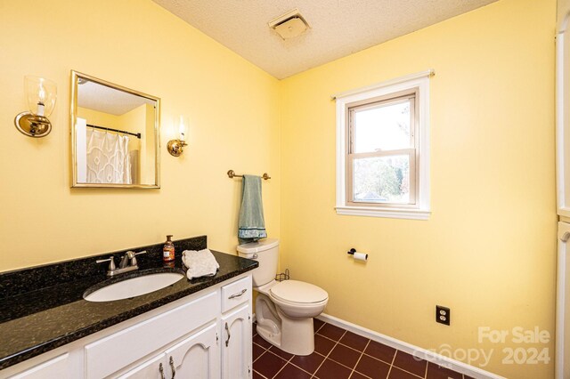 bathroom featuring tile patterned flooring, vanity, a textured ceiling, and toilet