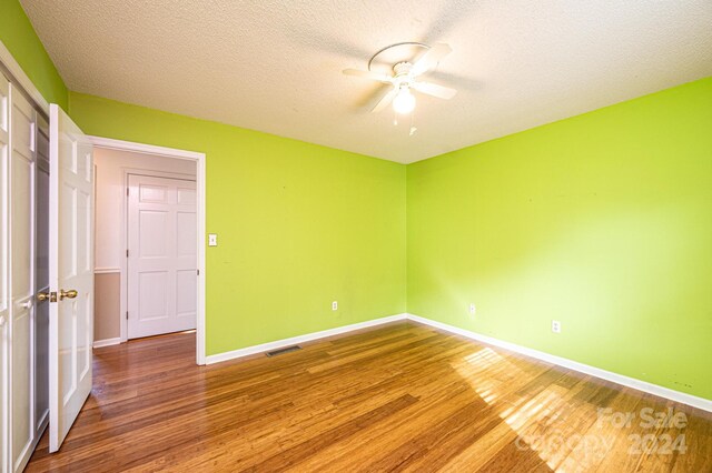 empty room featuring hardwood / wood-style floors, a textured ceiling, and ceiling fan