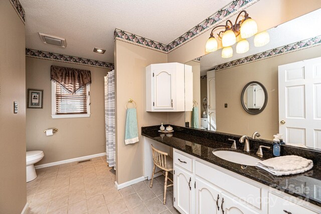 bathroom with tile patterned floors, vanity, toilet, and a textured ceiling