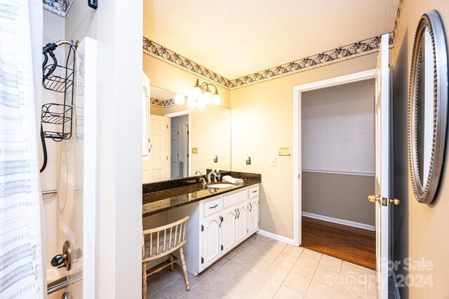 bathroom with hardwood / wood-style floors, vanity, a textured ceiling, and shower / bath combo