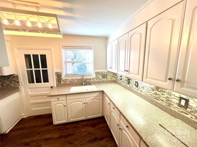 kitchen with backsplash, crown molding, dark wood-type flooring, sink, and white cabinets