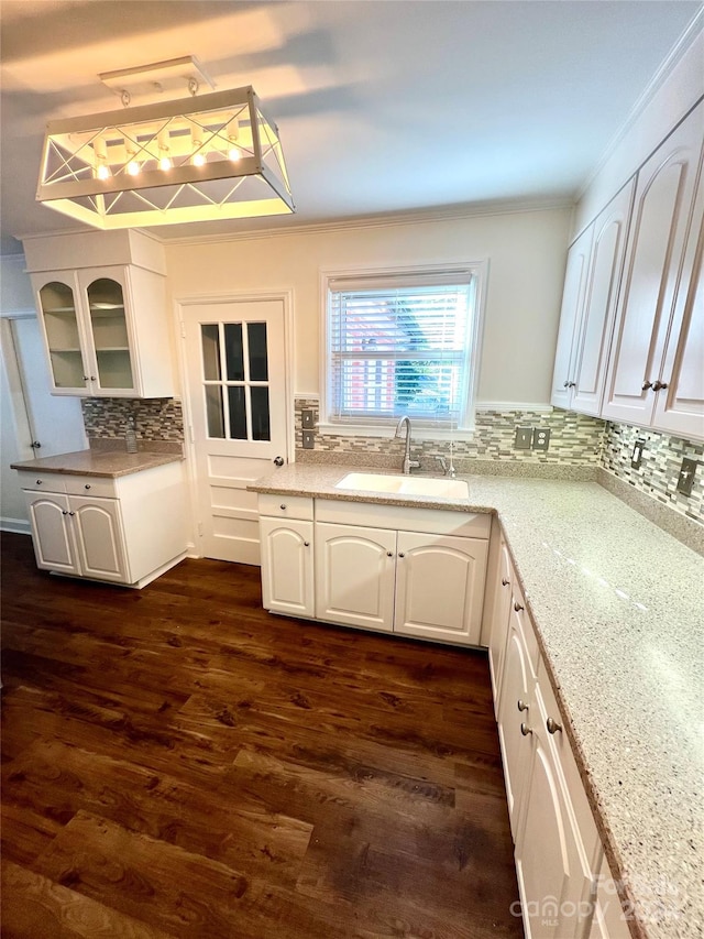 kitchen with backsplash, sink, dark hardwood / wood-style flooring, light stone counters, and white cabinetry