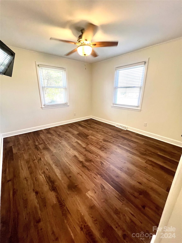 unfurnished room featuring ceiling fan, dark hardwood / wood-style flooring, and a healthy amount of sunlight