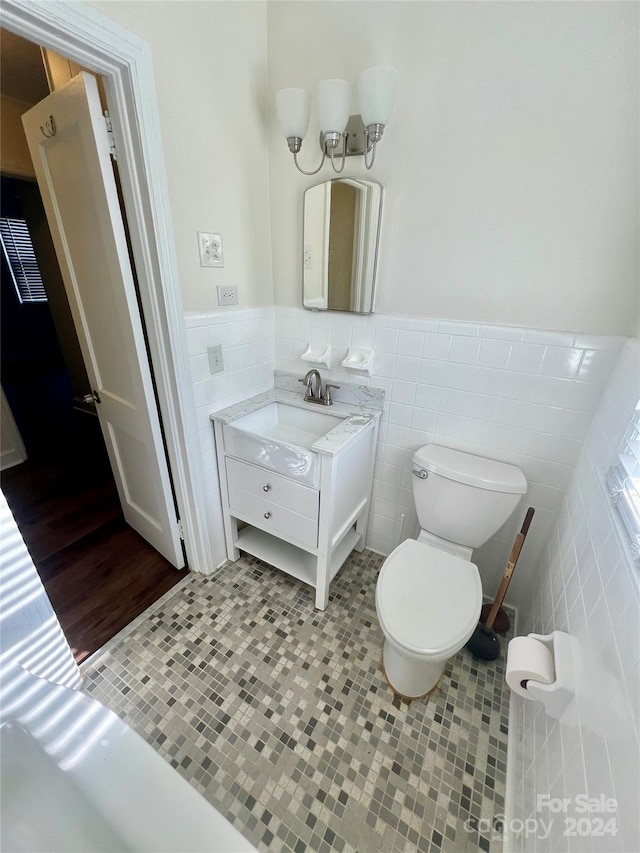 bathroom with vanity, tile walls, and toilet