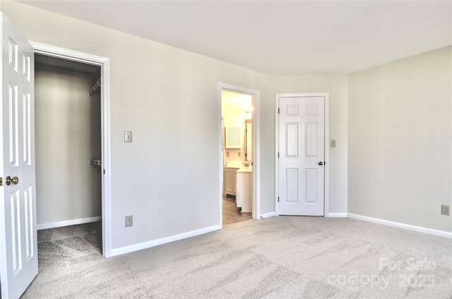 unfurnished bedroom featuring ensuite bathroom, a walk in closet, and carpet floors