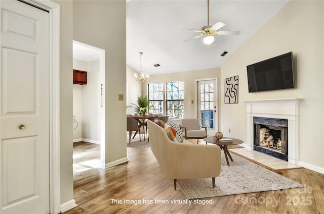 living room featuring ceiling fan with notable chandelier, light hardwood / wood-style flooring, and high vaulted ceiling