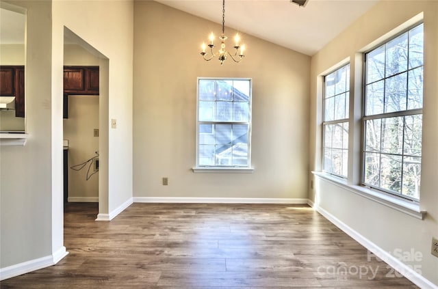 unfurnished dining area with lofted ceiling, dark hardwood / wood-style floors, and a chandelier