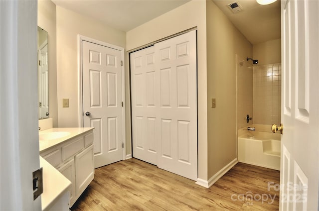 bathroom with vanity, wood-type flooring, and tiled shower / bath