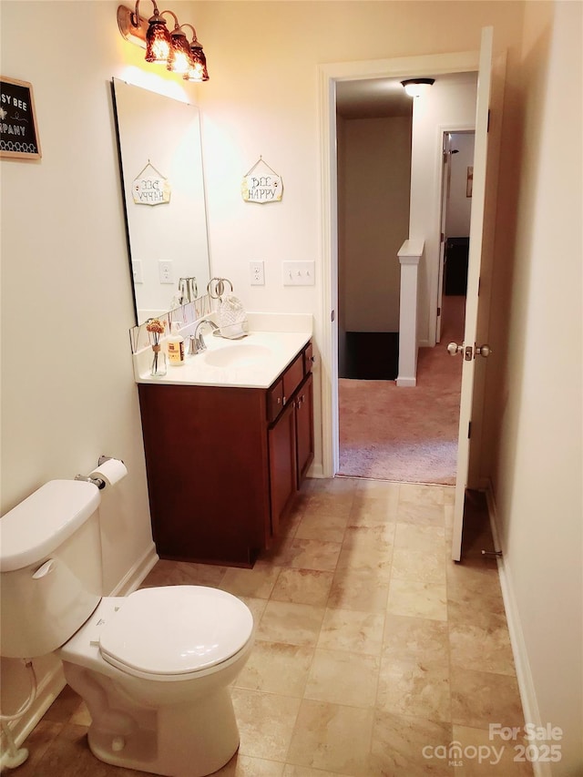 bathroom featuring toilet, vanity, and baseboards