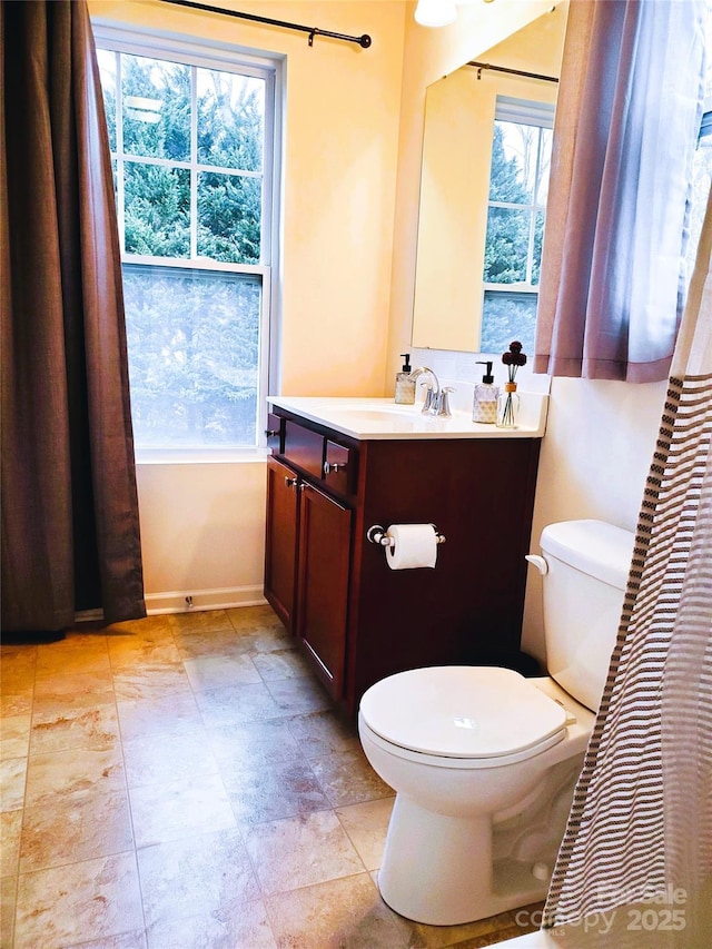 bathroom with toilet, healthy amount of natural light, vanity, and baseboards