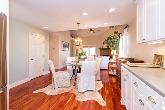 dining area featuring a tile fireplace, ceiling fan with notable chandelier, dark hardwood / wood-style floors, and sink