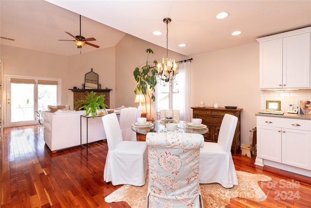 dining room with dark hardwood / wood-style floors, ceiling fan with notable chandelier, and vaulted ceiling