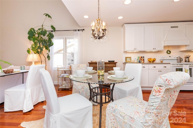 dining area featuring light wood-type flooring, an inviting chandelier, and vaulted ceiling