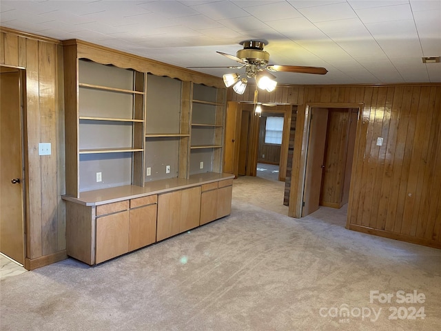 kitchen featuring wood walls, ceiling fan, and light colored carpet