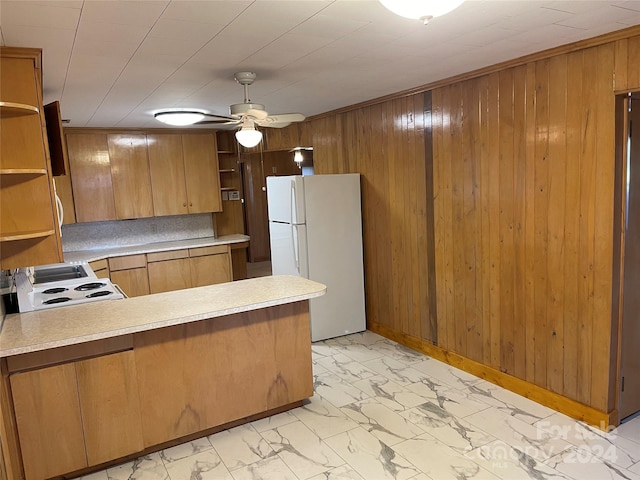 kitchen with kitchen peninsula, white appliances, ceiling fan, and wood walls