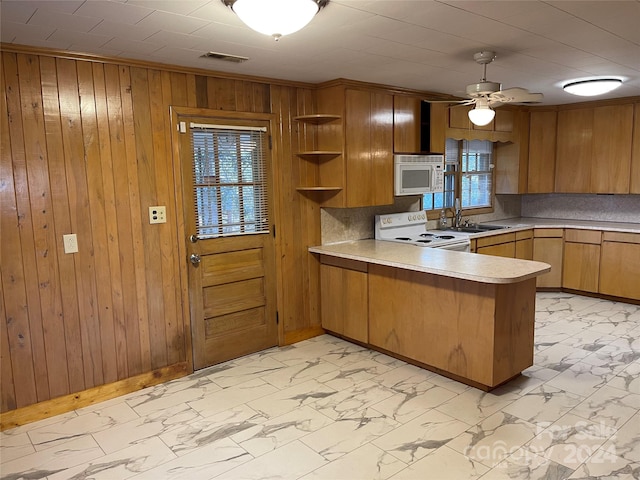 kitchen featuring kitchen peninsula, wooden walls, a healthy amount of sunlight, and white appliances