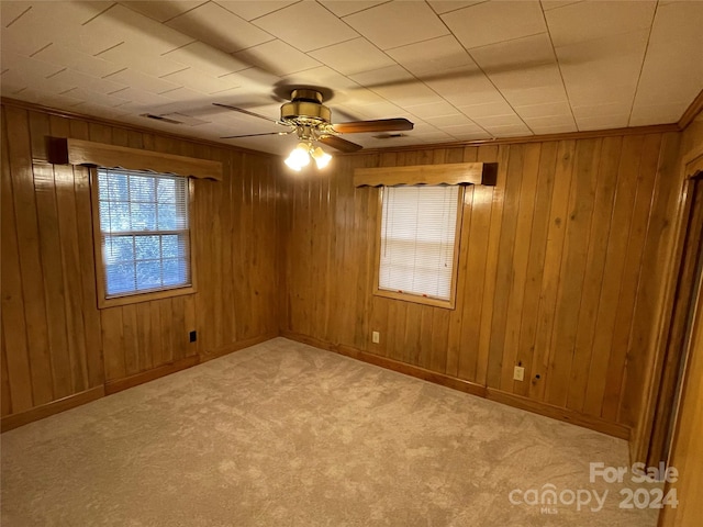 spare room with light colored carpet, ceiling fan, and wooden walls