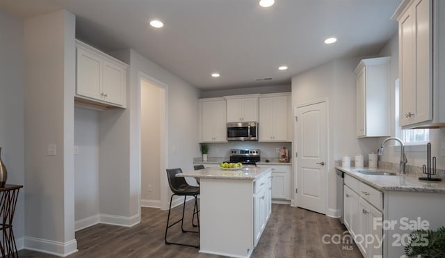 kitchen with appliances with stainless steel finishes, a center island, sink, and white cabinets