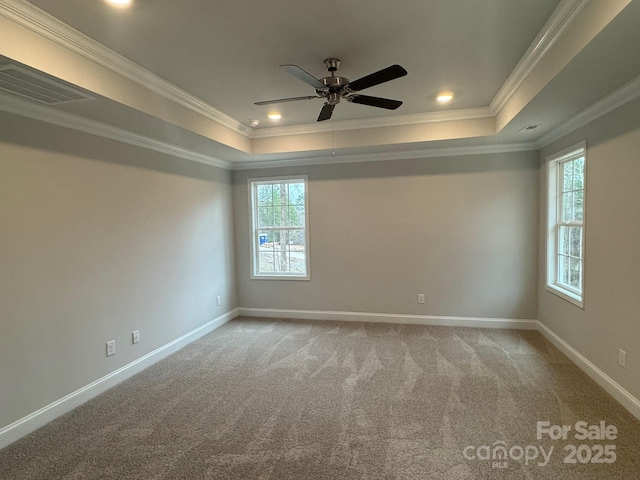 empty room with light carpet, a tray ceiling, crown molding, and ceiling fan