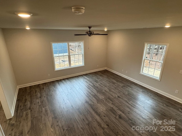 spare room with dark hardwood / wood-style flooring, a wealth of natural light, and ceiling fan