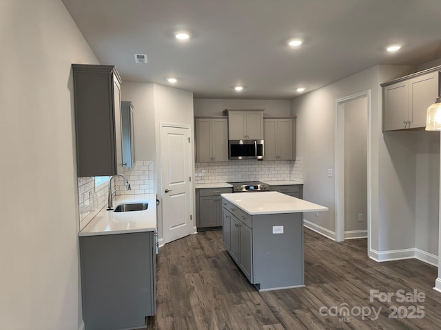 kitchen with a center island, stainless steel appliances, gray cabinets, and sink