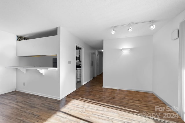 interior space with rail lighting, dark wood-type flooring, and a textured ceiling