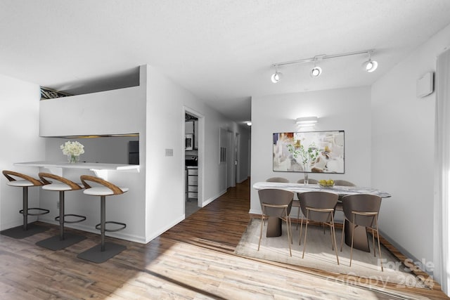 dining area featuring dark hardwood / wood-style flooring, rail lighting, and a textured ceiling