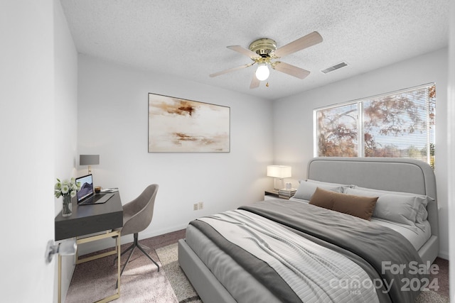 carpeted bedroom with ceiling fan and a textured ceiling