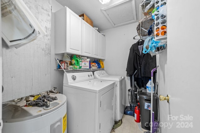 laundry area featuring washing machine and dryer, water heater, cabinets, and a textured ceiling