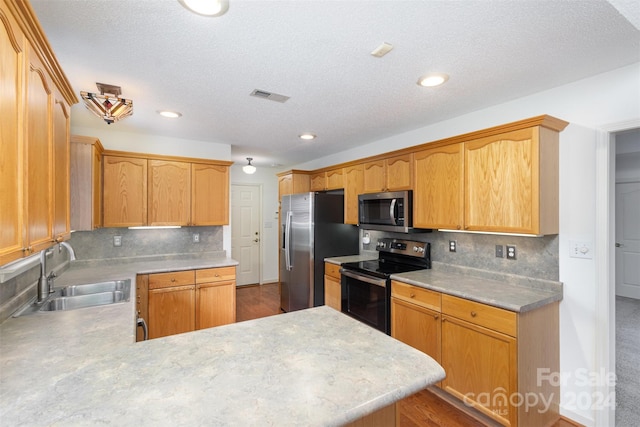 kitchen featuring sink, a textured ceiling, appliances with stainless steel finishes, tasteful backsplash, and kitchen peninsula