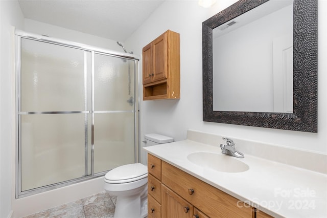 bathroom with a textured ceiling, vanity, toilet, and walk in shower