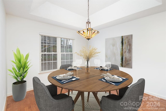 dining space with hardwood / wood-style floors and a raised ceiling