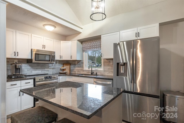 kitchen with white cabinets, decorative light fixtures, a kitchen island, and stainless steel appliances