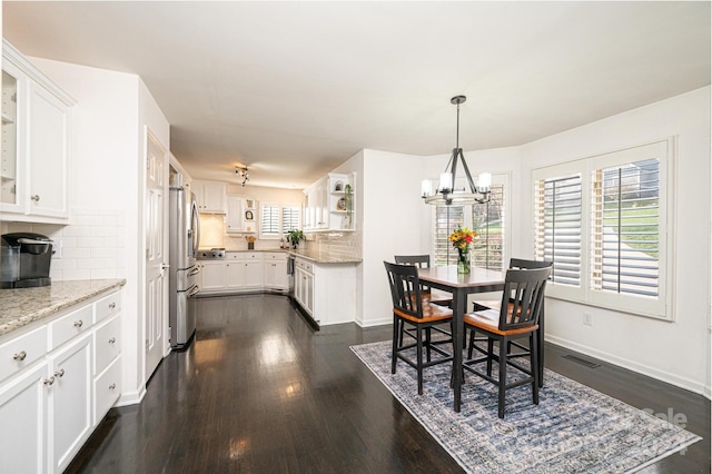 dining area with dark wood-type flooring and an inviting chandelier