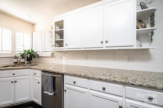 kitchen with white cabinetry, sink, light stone counters, stainless steel dishwasher, and decorative backsplash